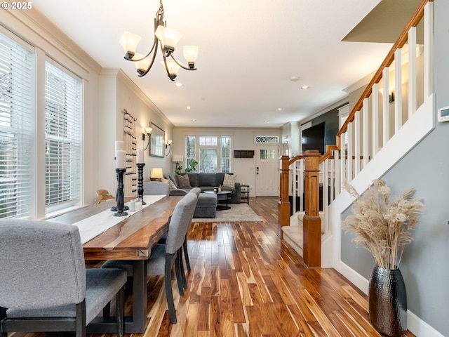 dining room with hardwood / wood-style floors, crown molding, and a notable chandelier