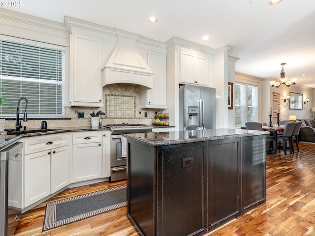 kitchen featuring premium range hood, sink, a center island, dark stone countertops, and stainless steel appliances