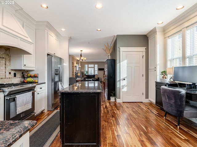 kitchen featuring dark stone countertops, white cabinets, hardwood / wood-style flooring, a center island, and stainless steel appliances