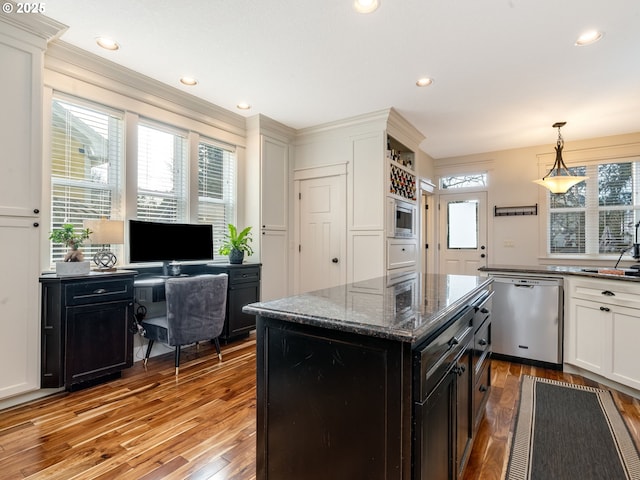 kitchen with white cabinets, appliances with stainless steel finishes, a wealth of natural light, and dark stone countertops