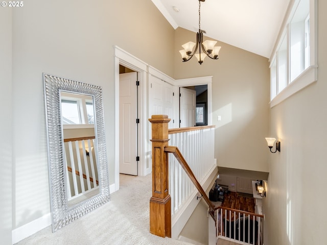 stairway featuring a notable chandelier, high vaulted ceiling, and carpet flooring