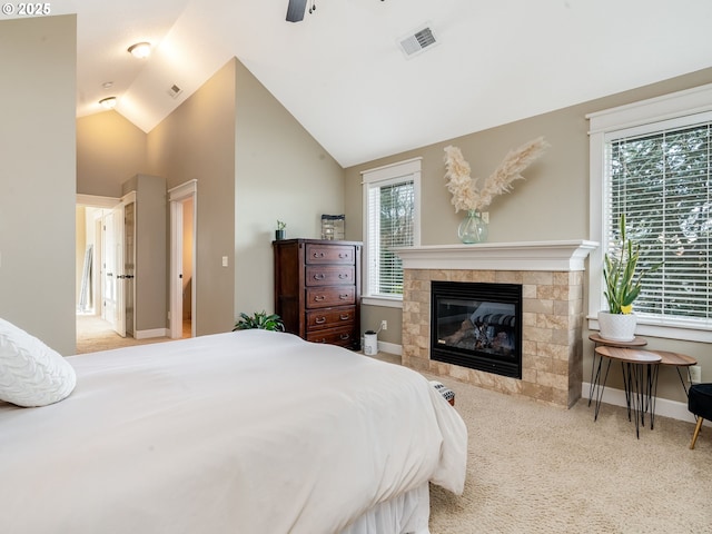 bedroom featuring ceiling fan, lofted ceiling, a tiled fireplace, and light carpet