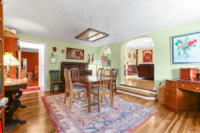 26011 S Morgan Rd, Estacada, OR 97023 - dining room featuring a textured ceiling, arched walkways, hardwood / wood-style floors, and baseboards