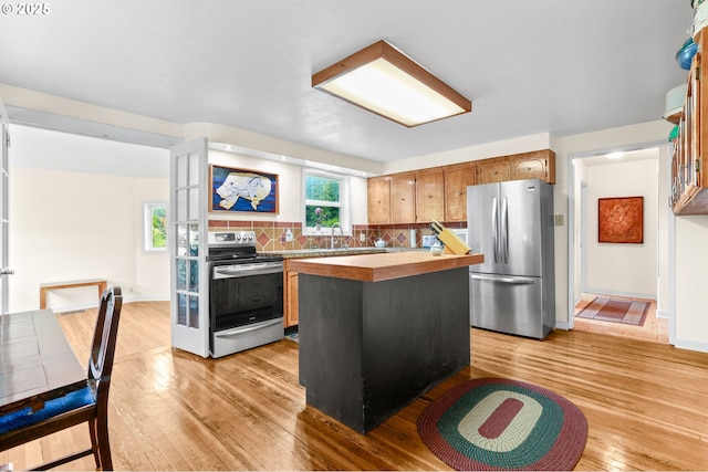 26011 S Morgan Rd, Estacada, OR 97023 - kitchen featuring appliances with stainless steel finishes, butcher block counters, light wood finished floors, backsplash, and a kitchen island