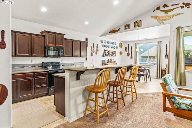 5739 Donohoe Ave, Eugene, OR 97402 - kitchen featuring black appliances, lofted ceiling, an island with sink, dark brown cabinetry, and a kitchen bar