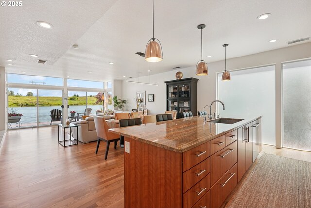 14569 NW Larson Rd Unit 13, Portland, OR 97231 - kitchen featuring an island with sink, light wood-style floors, recessed lighting, expansive windows, and brown cabinetry