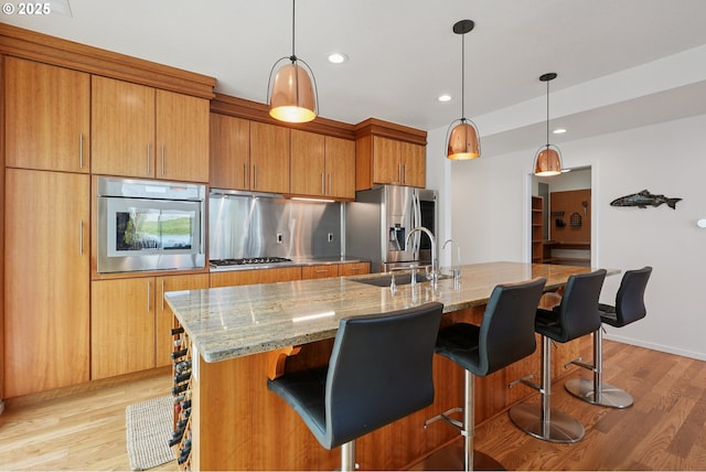 14569 NW Larson Rd Unit 13, Portland, OR 97231 - kitchen with stainless steel appliances, light wood finished floors, light stone countertops, brown cabinets, and recessed lighting