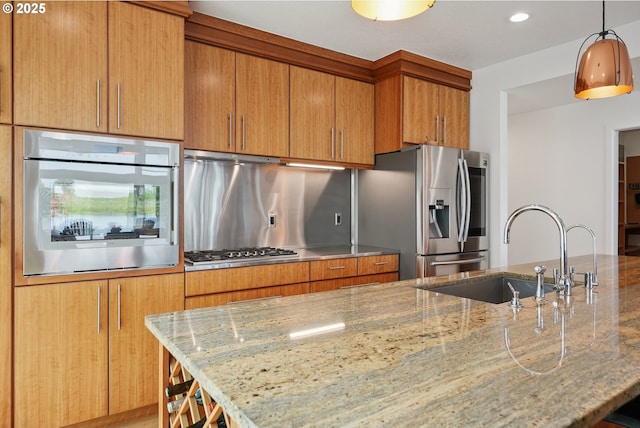 14569 NW Larson Rd Unit 13, Portland, OR 97231 - kitchen with appliances with stainless steel finishes, light stone counters, brown cabinets, hanging light fixtures, and recessed lighting