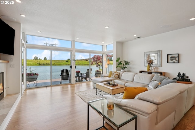 14569 NW Larson Rd Unit 13, Portland, OR 97231 - living room with a glass covered fireplace, expansive windows, light wood-type flooring, a water view, and recessed lighting