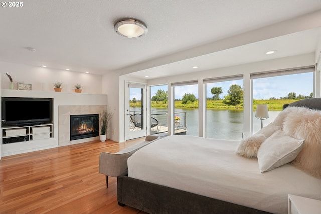 14569 NW Larson Rd Unit 13, Portland, OR 97231 - bedroom with access to outside, wood finished floors, a water view, a tiled fireplace, and recessed lighting