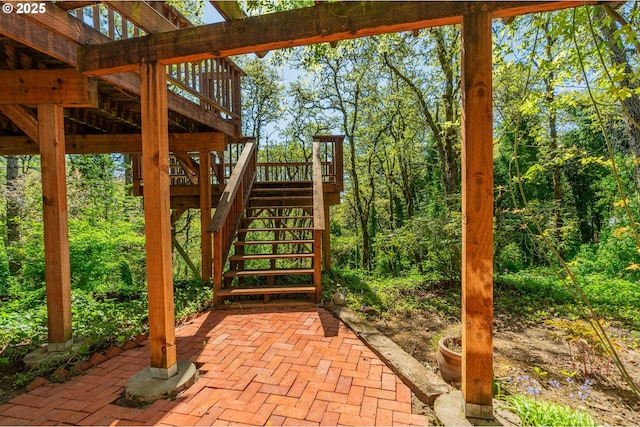 view of patio / terrace with a wooden deck, a forest view, and stairway