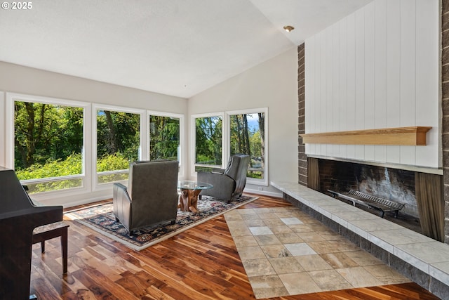 living room with wood-type flooring, lofted ceiling, and a tile fireplace