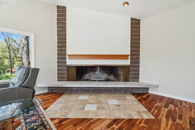 unfurnished living room with baseboards, wood finished floors, and a fireplace
