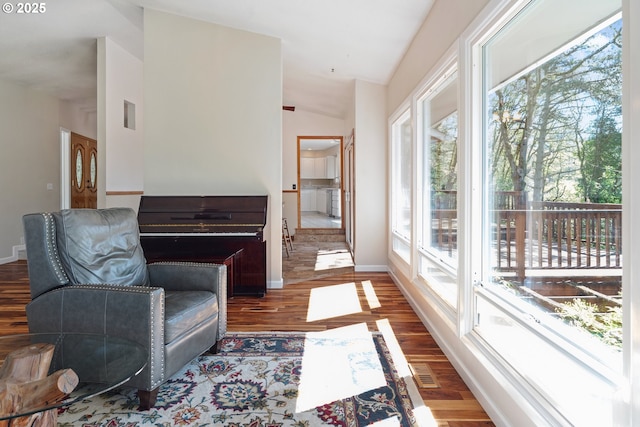 living area with vaulted ceiling, baseboards, wood finished floors, and visible vents
