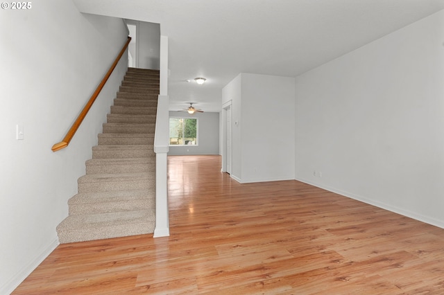 stairs with hardwood / wood-style floors and ceiling fan