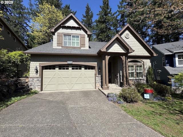 craftsman-style house with a shingled roof, stone siding, and driveway