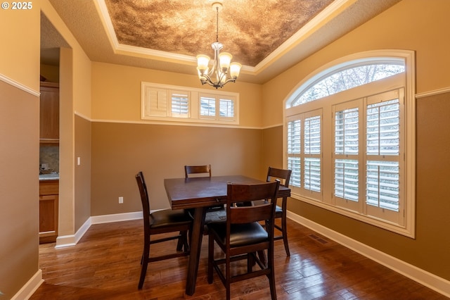 dining room featuring a tray ceiling, ornamental molding, a notable chandelier, dark wood-style floors, and baseboards