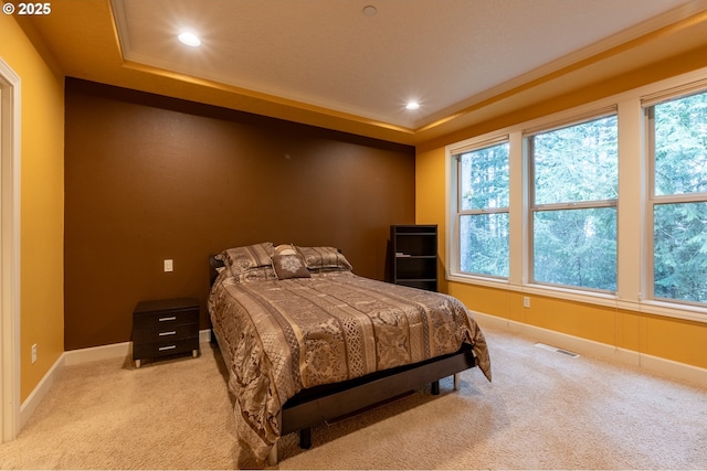 bedroom featuring baseboards, light carpet, recessed lighting, visible vents, and a tray ceiling