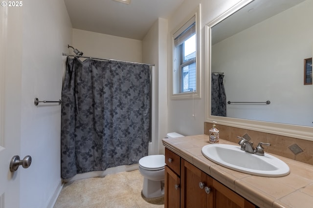 bathroom with toilet, vanity, and baseboards