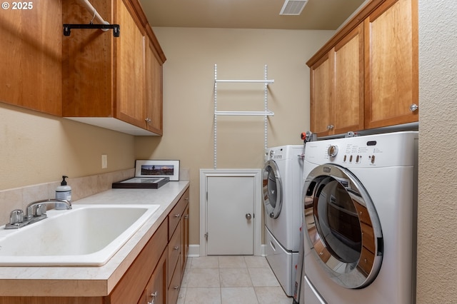 laundry area with visible vents, light tile patterned floors, washer and dryer, a sink, and cabinet space