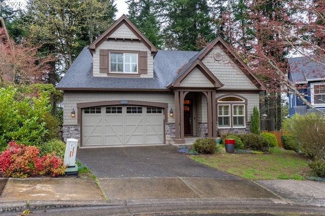 craftsman inspired home with roof with shingles, driveway, stone siding, and an attached garage