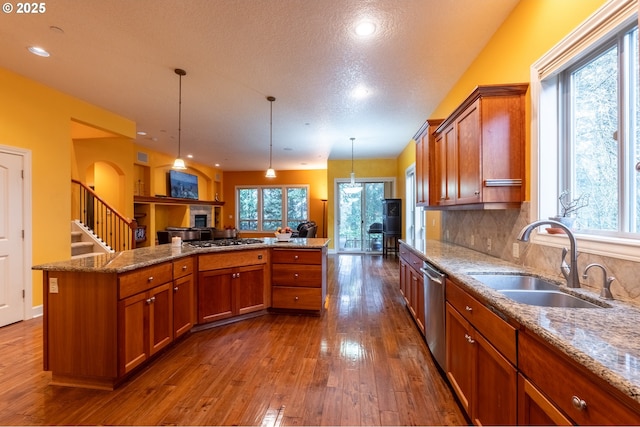 kitchen with a sink, appliances with stainless steel finishes, dark wood finished floors, a healthy amount of sunlight, and brown cabinets