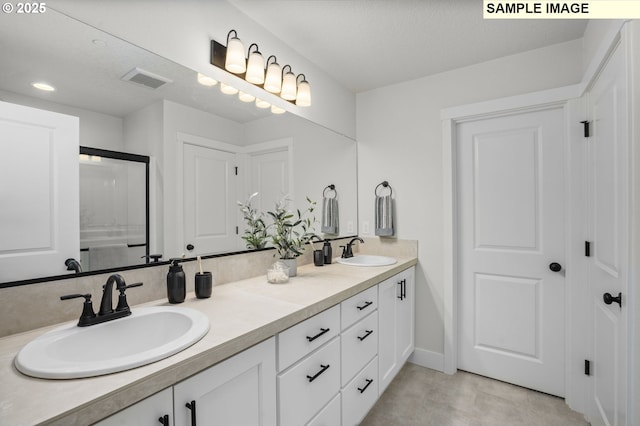 bathroom with visible vents, double vanity, and a sink