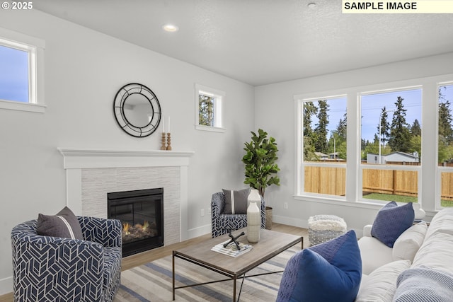 living room featuring recessed lighting, baseboards, wood finished floors, and a fireplace