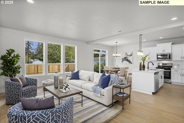 living room with recessed lighting, a textured ceiling, a chandelier, and light wood-type flooring