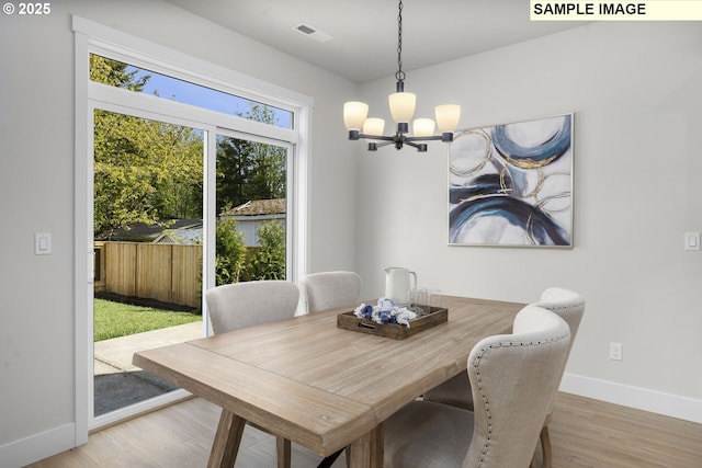 dining area with visible vents, wood finished floors, a chandelier, and baseboards