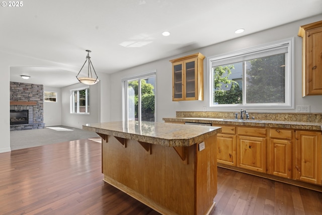 3504 NE Garfield St, Camas, WA 98607 - kitchen featuring a center island, a breakfast bar area, dark wood finished floors, glass insert cabinets, and a fireplace