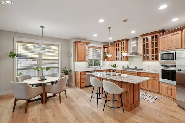915 NE 36th Ave, Camas, WA 98607 - kitchen featuring appliances with stainless steel finishes, wall chimney range hood, a kitchen island, decorative backsplash, and light wood-style flooring