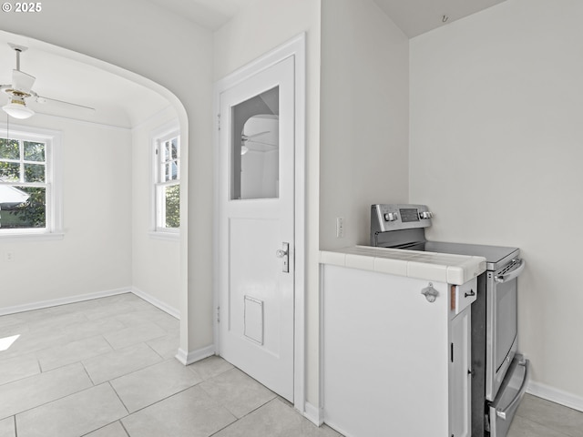 3310 NE 70th Ave, Portland, OR 97213 - laundry area featuring a ceiling fan, baseboards, light tile patterned floors, and arched walkways