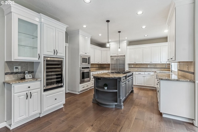 kitchen featuring wine cooler, white cabinets, an island with sink, and built in appliances