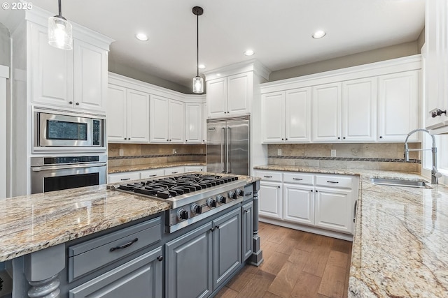 kitchen with gray cabinets, dark wood-type flooring, white cabinetry, a sink, and built in appliances