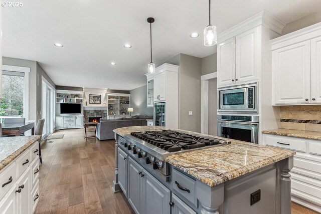 kitchen featuring appliances with stainless steel finishes, gray cabinets, white cabinetry, and a stone fireplace