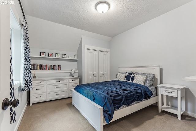 bedroom featuring lofted ceiling, a closet, light colored carpet, a textured ceiling, and baseboards