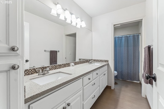 full bathroom with double vanity, a sink, toilet, and decorative backsplash