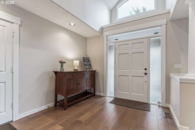 entrance foyer with decorative columns, visible vents, a high ceiling, wood finished floors, and baseboards