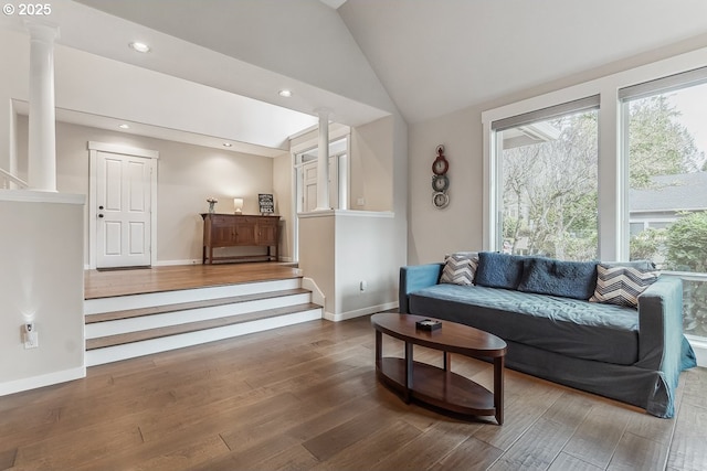 living area with vaulted ceiling, plenty of natural light, wood finished floors, and ornate columns