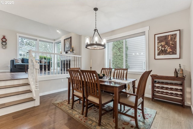 dining space featuring baseboards, wood-type flooring, and a notable chandelier