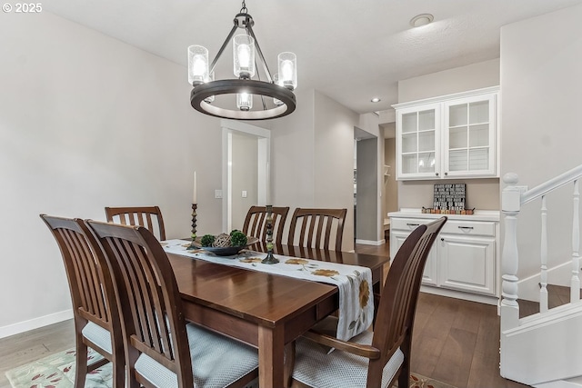 dining space with stairway, a notable chandelier, baseboards, and dark wood-style flooring