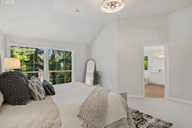 carpeted bedroom with ensuite bath and lofted ceiling