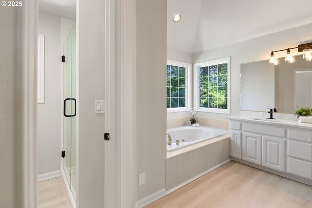 bathroom with lofted ceiling, plus walk in shower, vanity, and hardwood / wood-style flooring