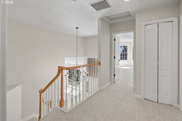 hallway featuring light colored carpet and a textured ceiling