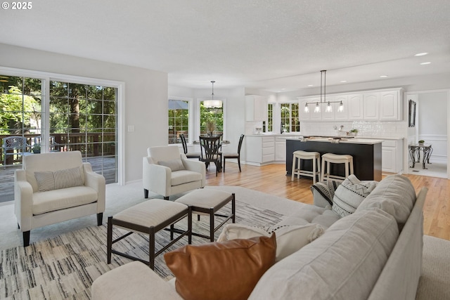 living room with a notable chandelier, light hardwood / wood-style flooring, and a textured ceiling