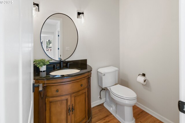 bathroom featuring toilet, vanity, and hardwood / wood-style floors