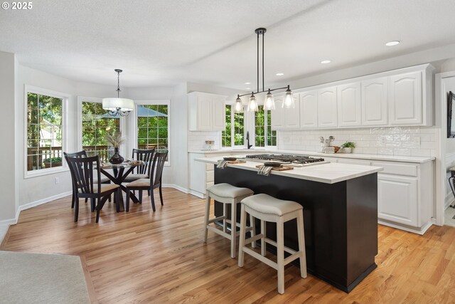 kitchen with decorative light fixtures, white cabinets, and a center island