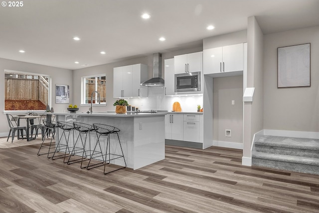 16779 SE Shimmering Leaf St, Happy Valley, OR 97086 - kitchen with wall chimney exhaust hood, stainless steel microwave, white cabinets, and a center island with sink
