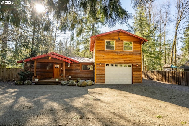 view of front of home featuring fence, driveway, metal roof, and an attached garage